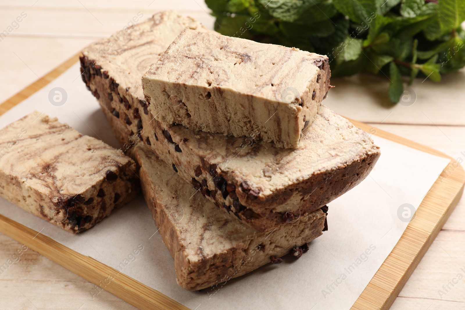 Photo of Pieces of tasty chocolate halva on wooden table, closeup