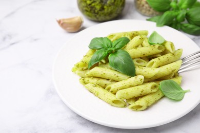 Photo of Delicious pasta with pesto sauce and basil on white marble table, closeup. Space for text