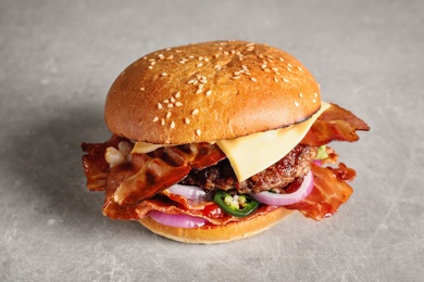 Photo of Tasty burger with bacon on grey background