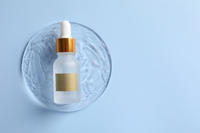 Bottle of cosmetic serum on light blue background, top view. Space for text