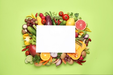 Fresh organic fruits, vegetables and blank card on green background, flat lay. Space for text