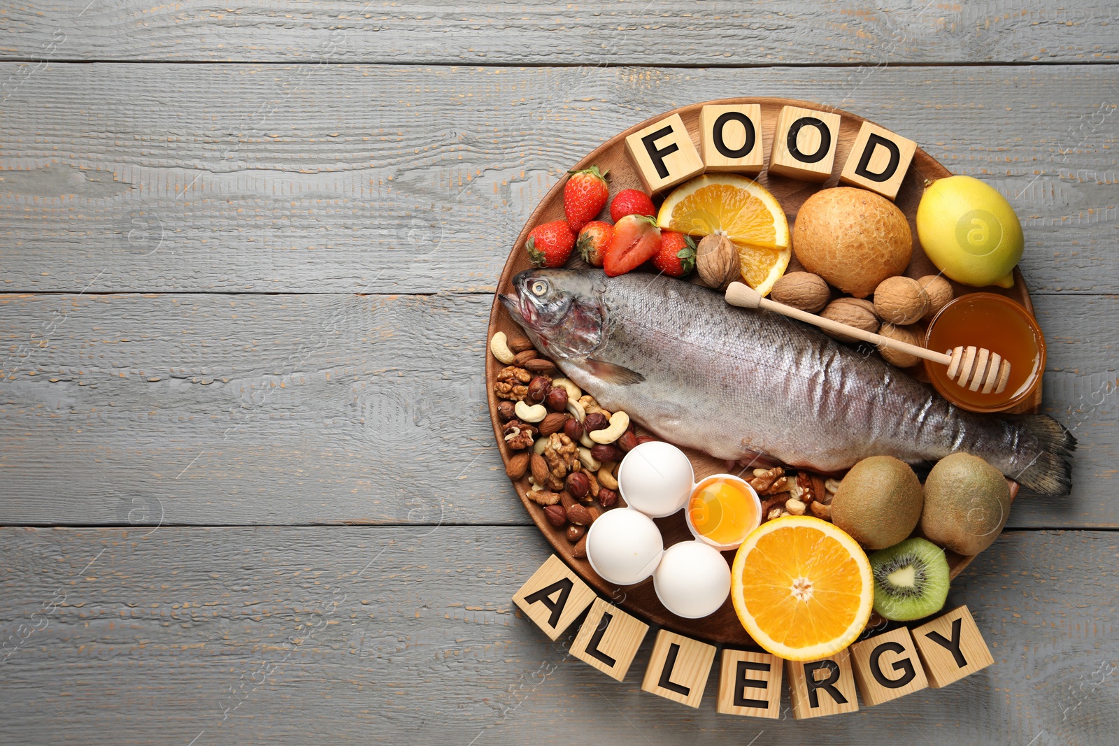 Image of Food allergy. Different fresh products and cubes on grey wooden table, top view with space for text