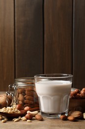 Vegan milk and different nuts on wooden table. Space for text
