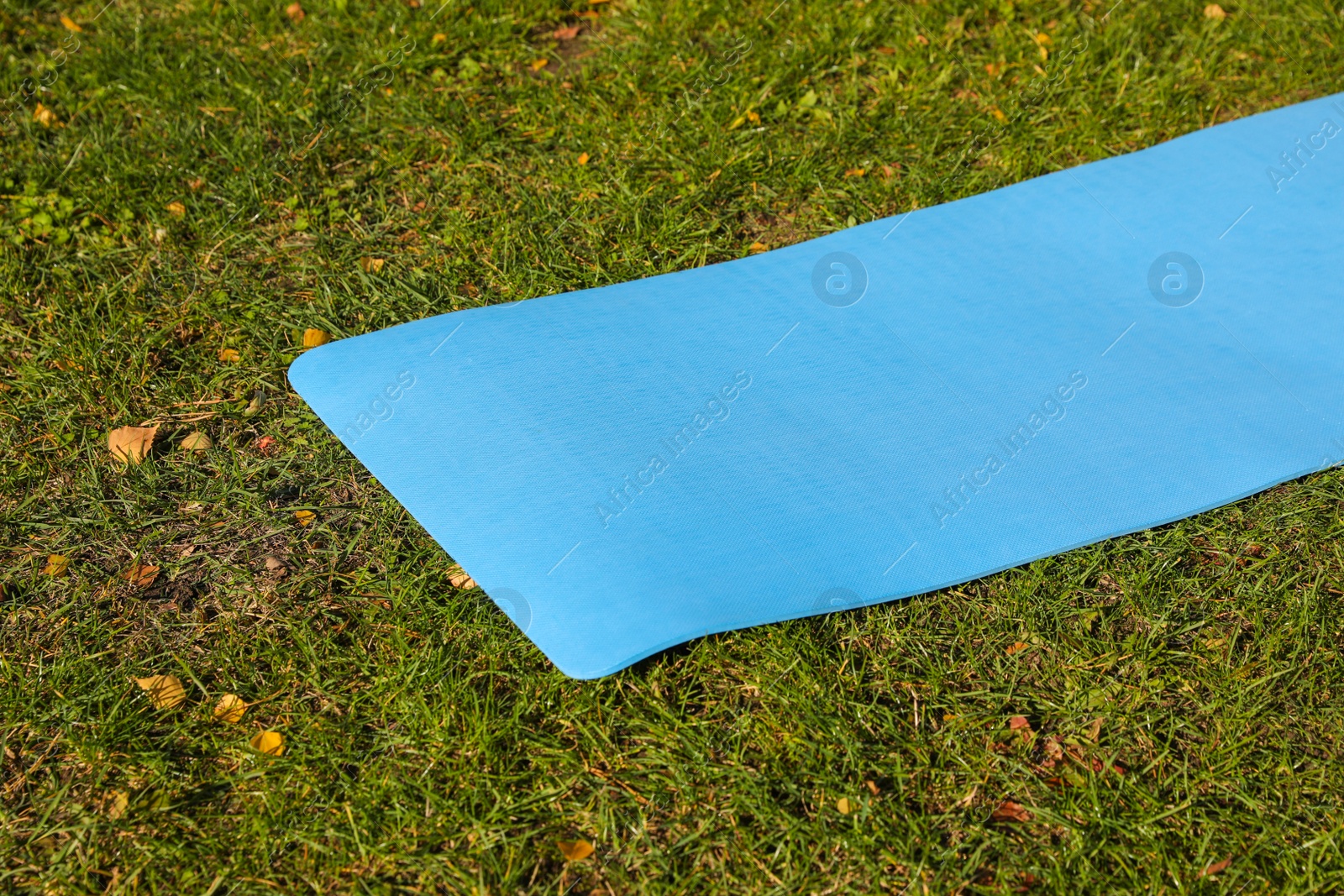 Photo of Blue karemat or fitness mat on fresh green grass outdoors