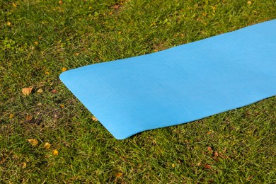 Photo of Blue karemat or fitness mat on fresh green grass outdoors