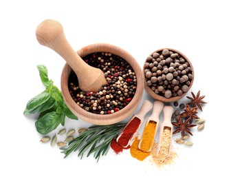 Mortar with pestle and different spices on white background, top view