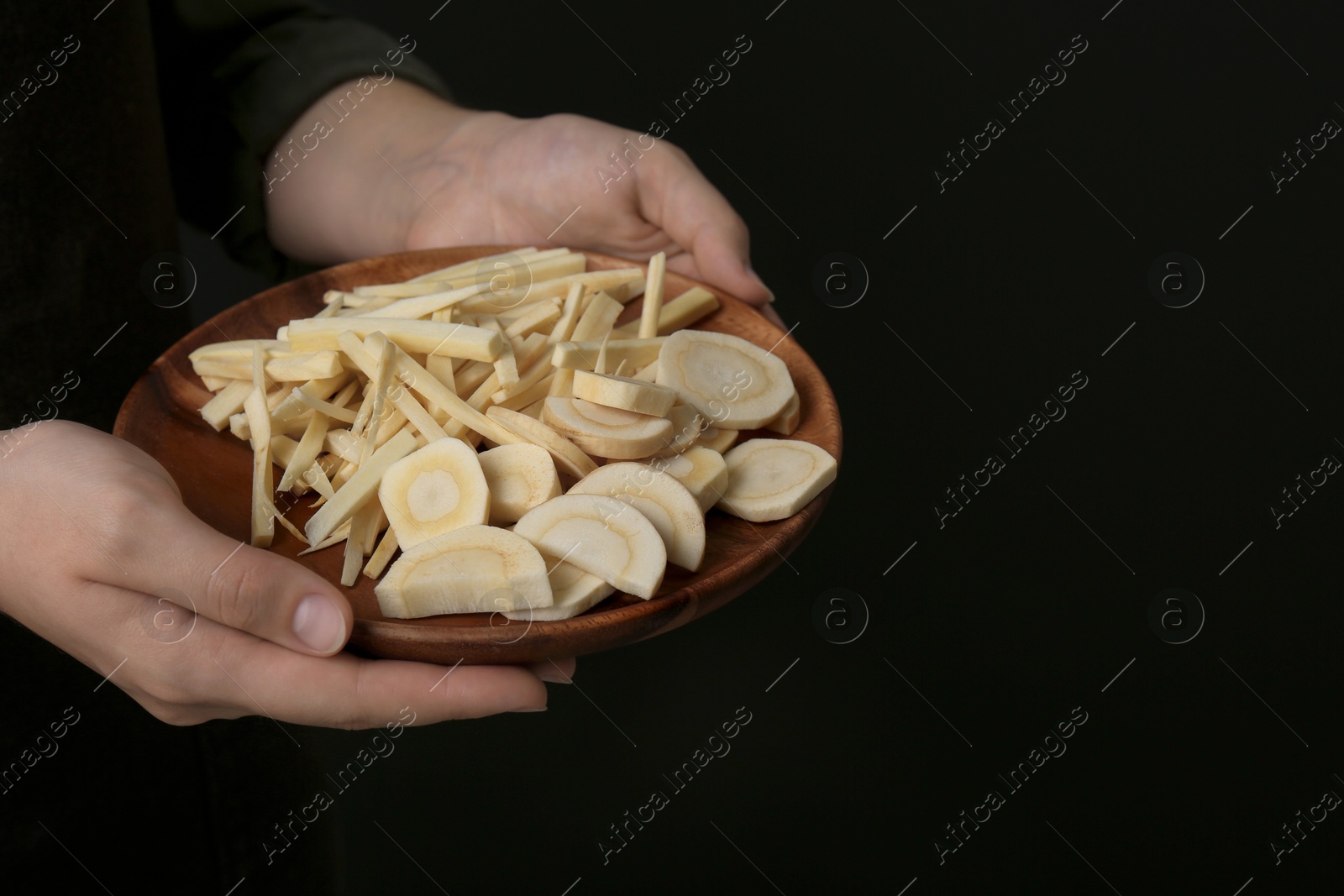 Photo of Woman holding plate with cut parsnips, closeup. Space for text