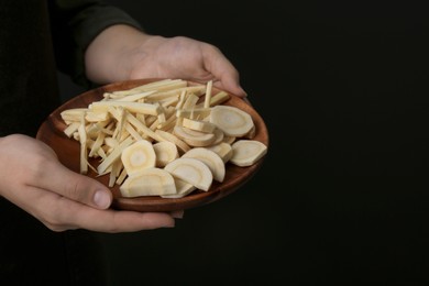 Woman holding plate with cut parsnips, closeup. Space for text