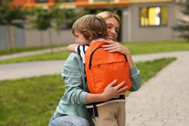 Photo of Happy woman hugging with her son near kindergarten outdoors