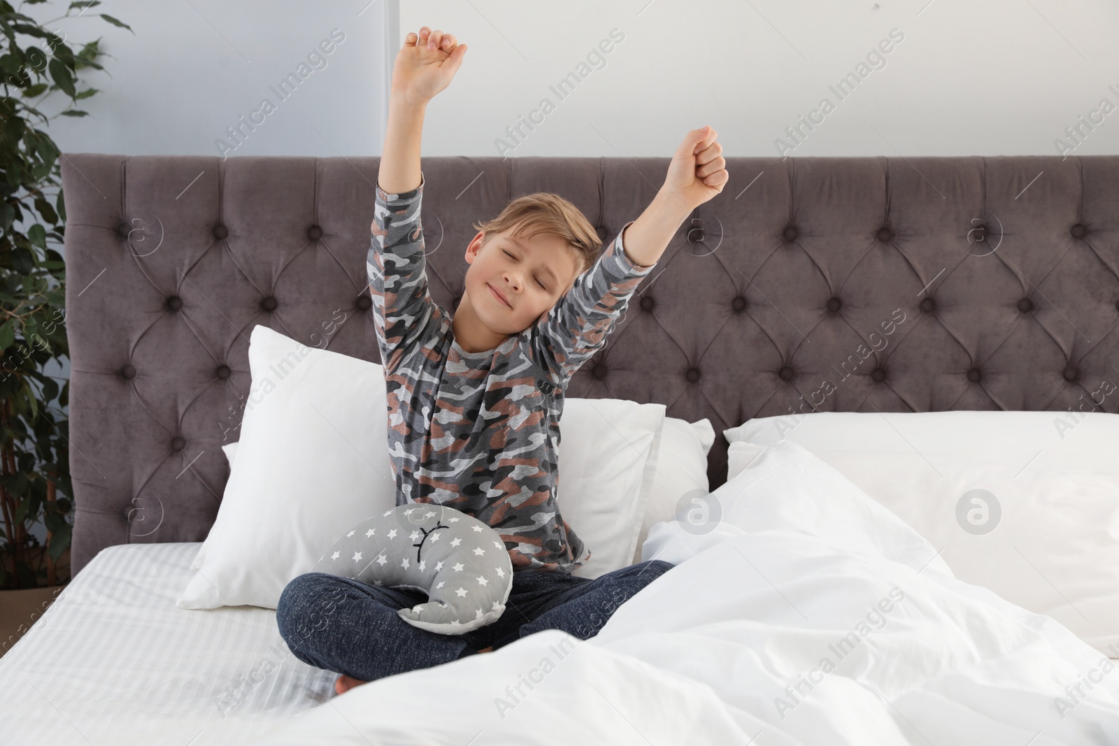 Photo of Cute boy with toy stretching after sleep on bed. Space for text