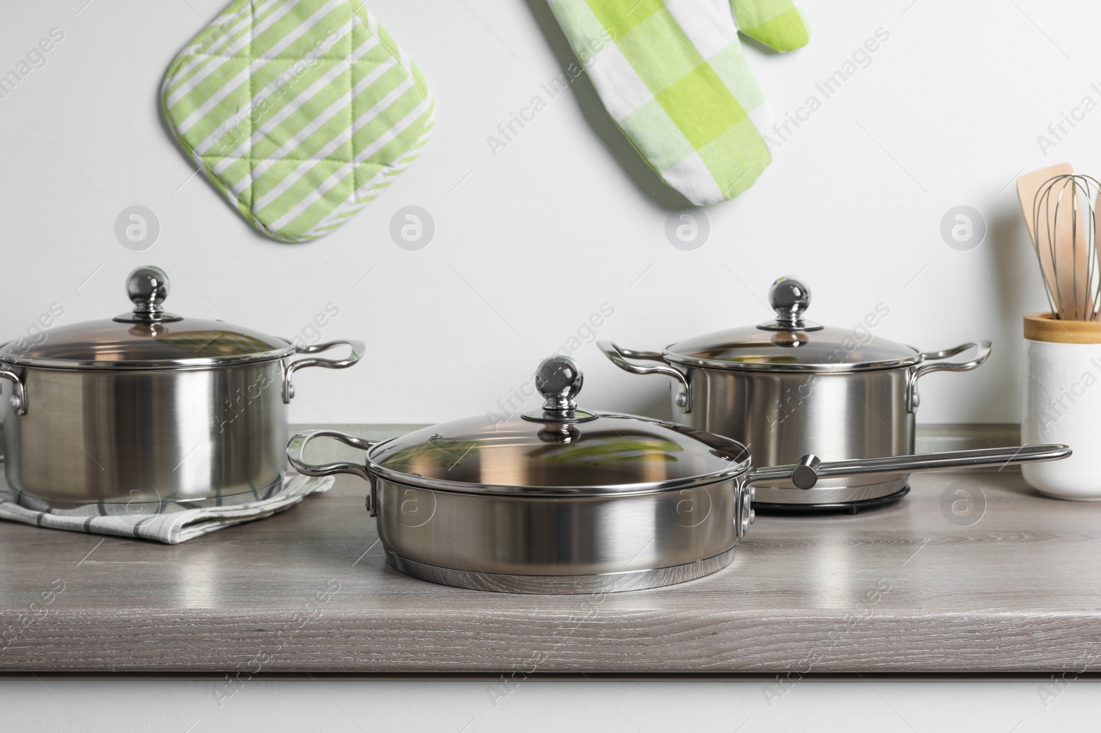 Photo of New cookware set on wooden countertop near light wall