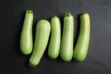 Photo of Raw green zucchinis on black slate table, flat lay