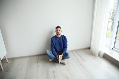 Photo of Handsome man with book on floor near wall at home