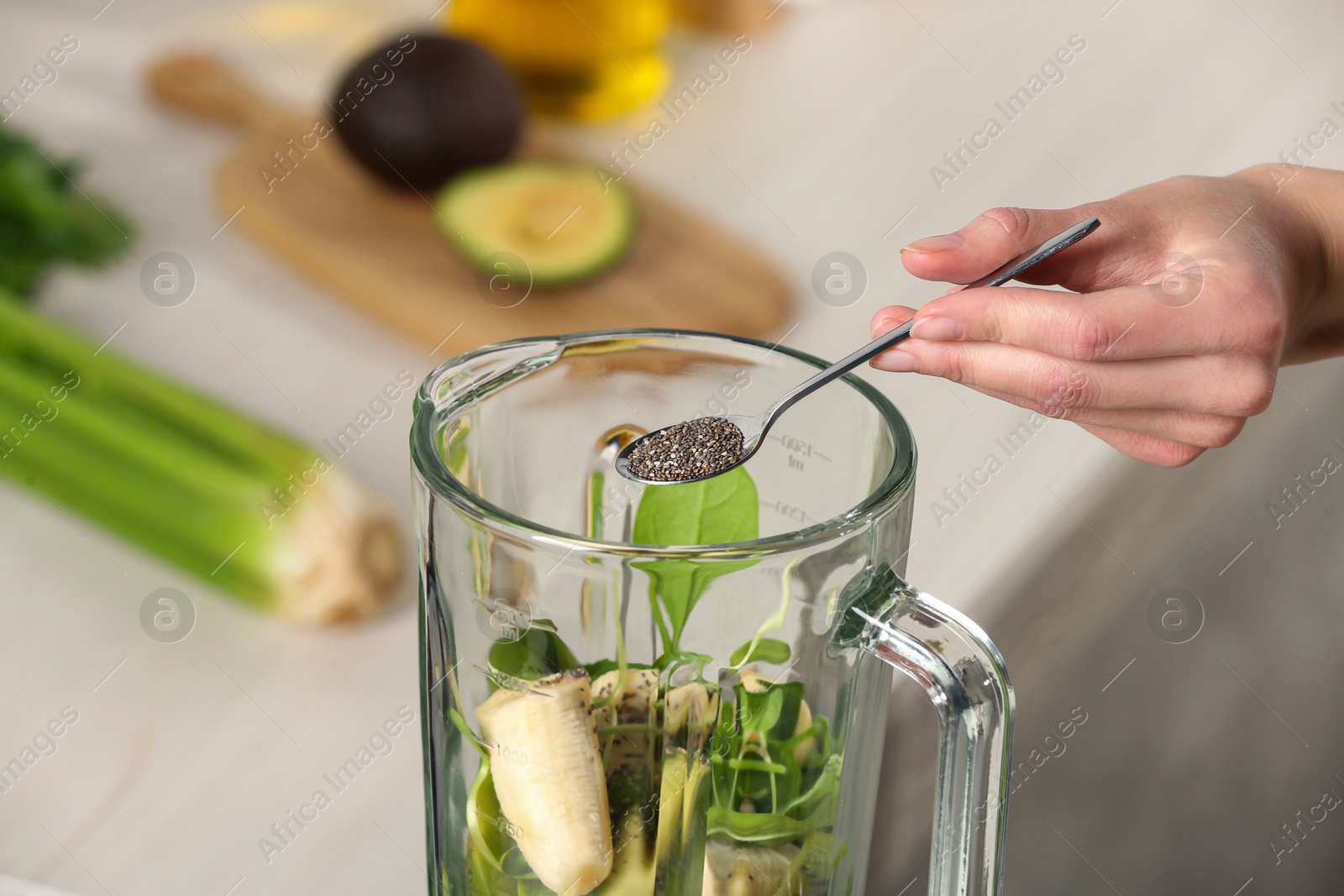 Photo of Woman adding chia seeds into blender with ingredients for green smoothie, closeup