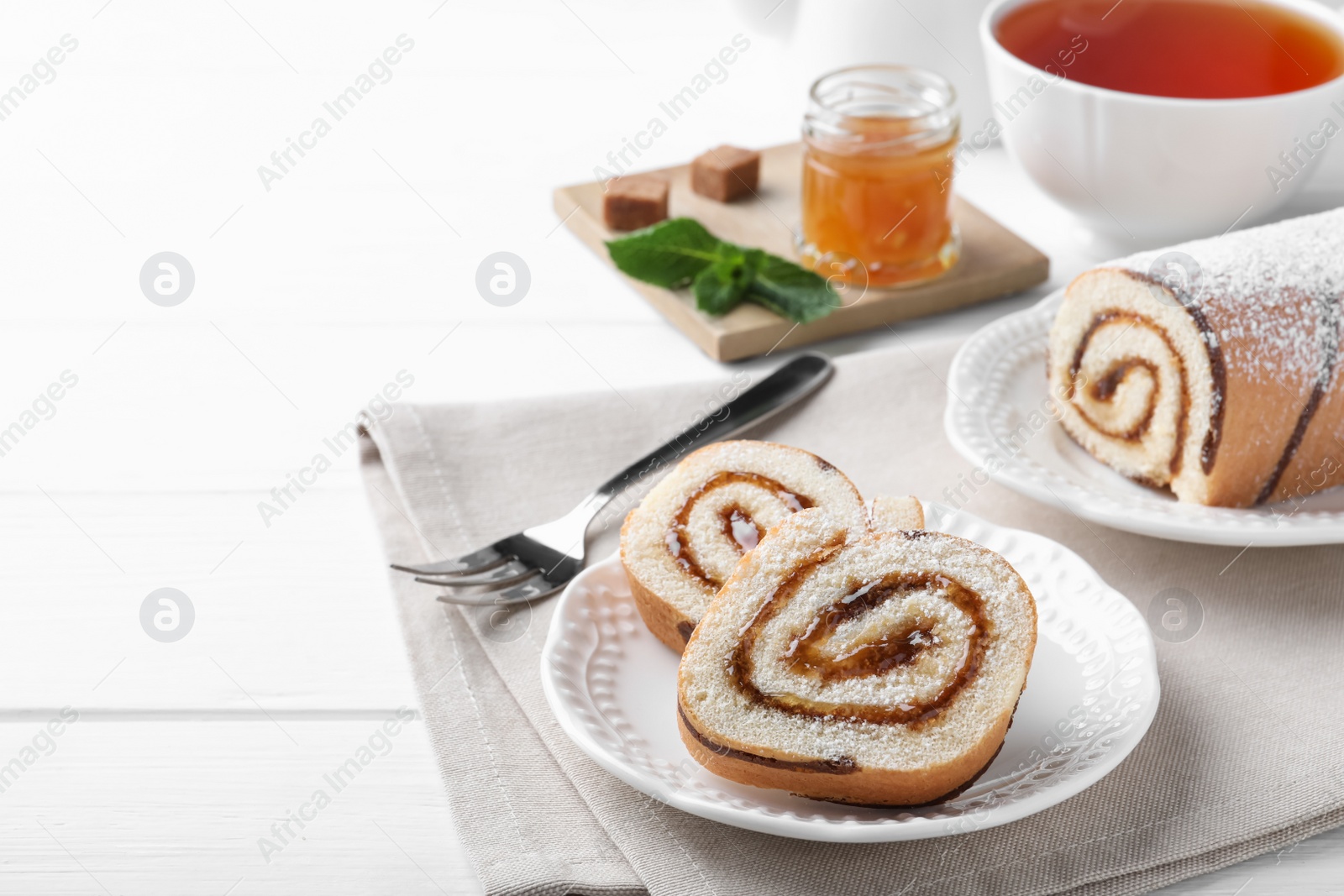 Photo of Tasty cake roll with jam on white wooden table, space for text
