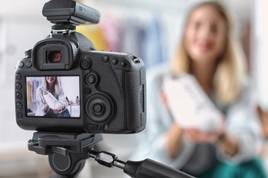 Fashion blogger recording video indoors, selective focus on camera display. Space for text