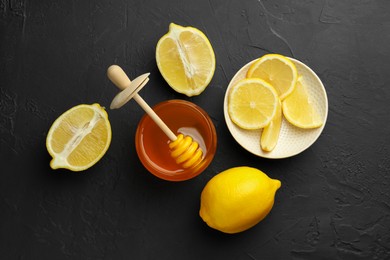 Photo of Sweet honey and fresh lemons on black table, flat lay