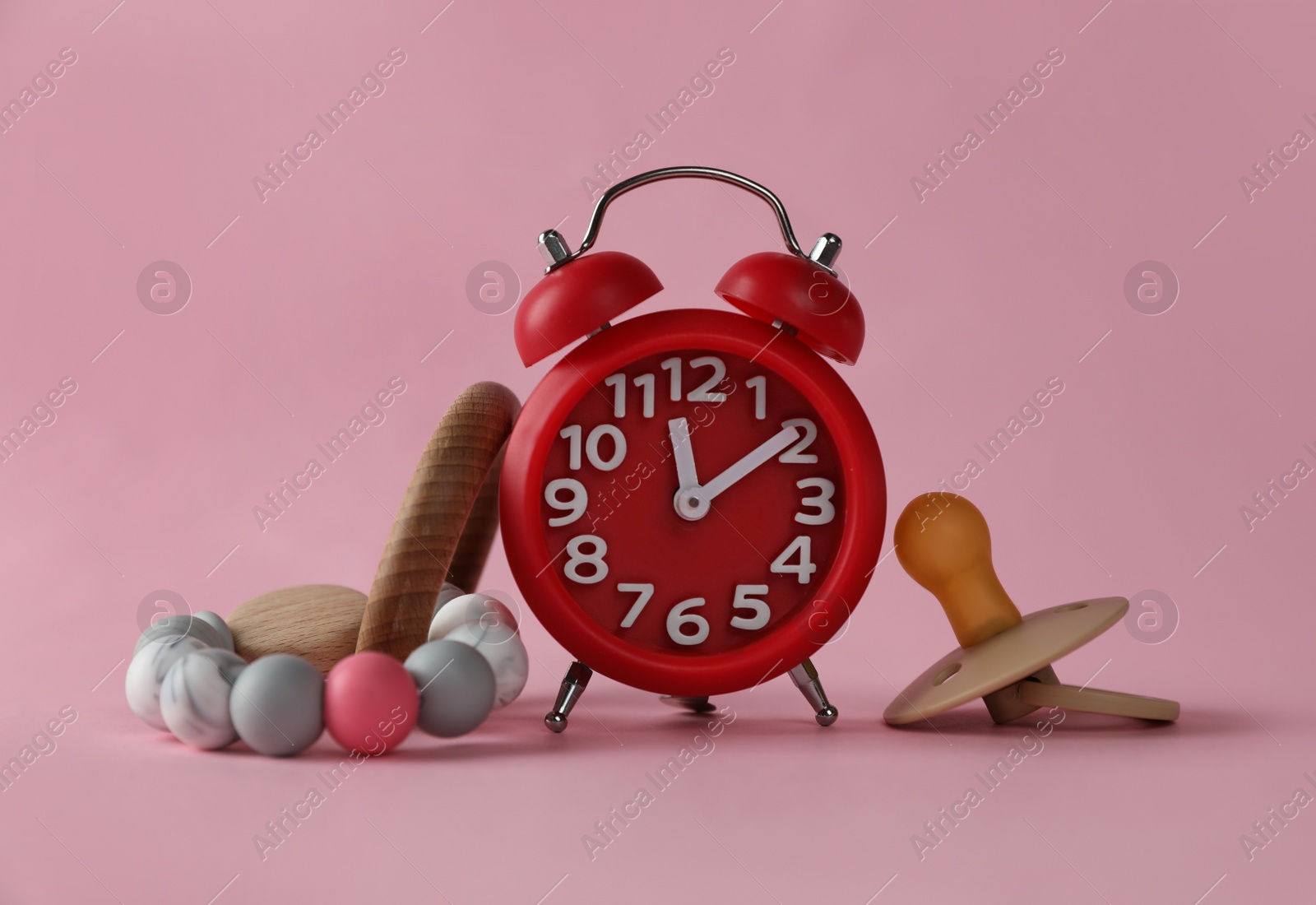 Photo of Alarm clock, baby dummy and toy on pink background. Time to give birth