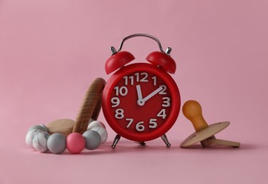 Photo of Alarm clock, baby dummy and toy on pink background. Time to give birth