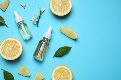 Photo of Flat lay composition with bottles of citrus essential oil on light blue background. Space for text