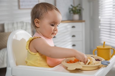 Photo of Cute little baby wearing bib while eating at home