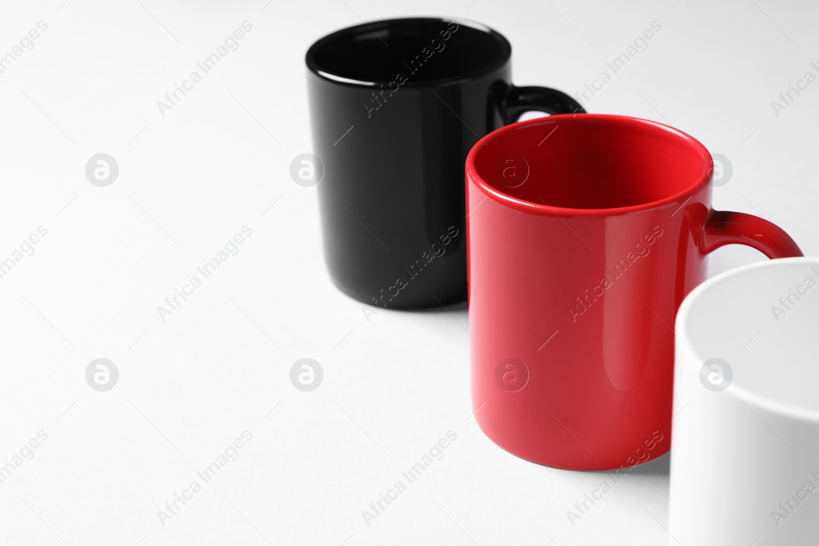 Colorful ceramic mugs on light background, closeup. Space for text Photo of Colorful ceramic mugs on light background, closeup. Space for text