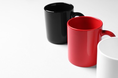 Photo of Colorful ceramic mugs on light background, closeup. Space for text