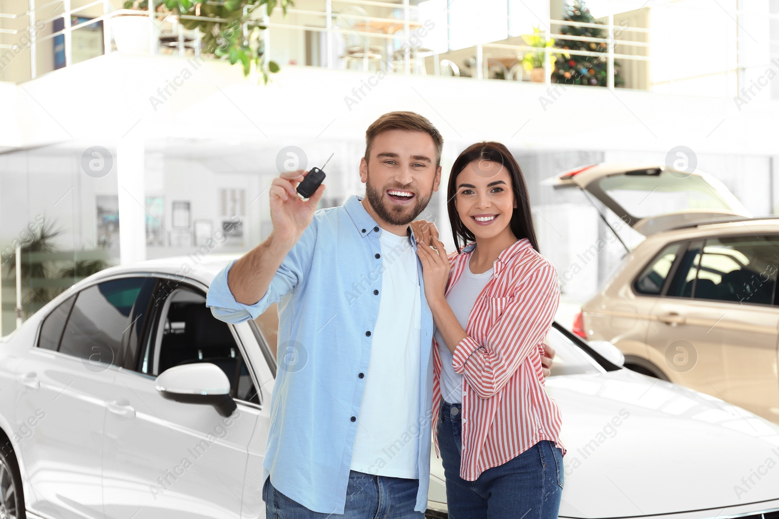 Photo of Happy couple with car key in modern auto dealership