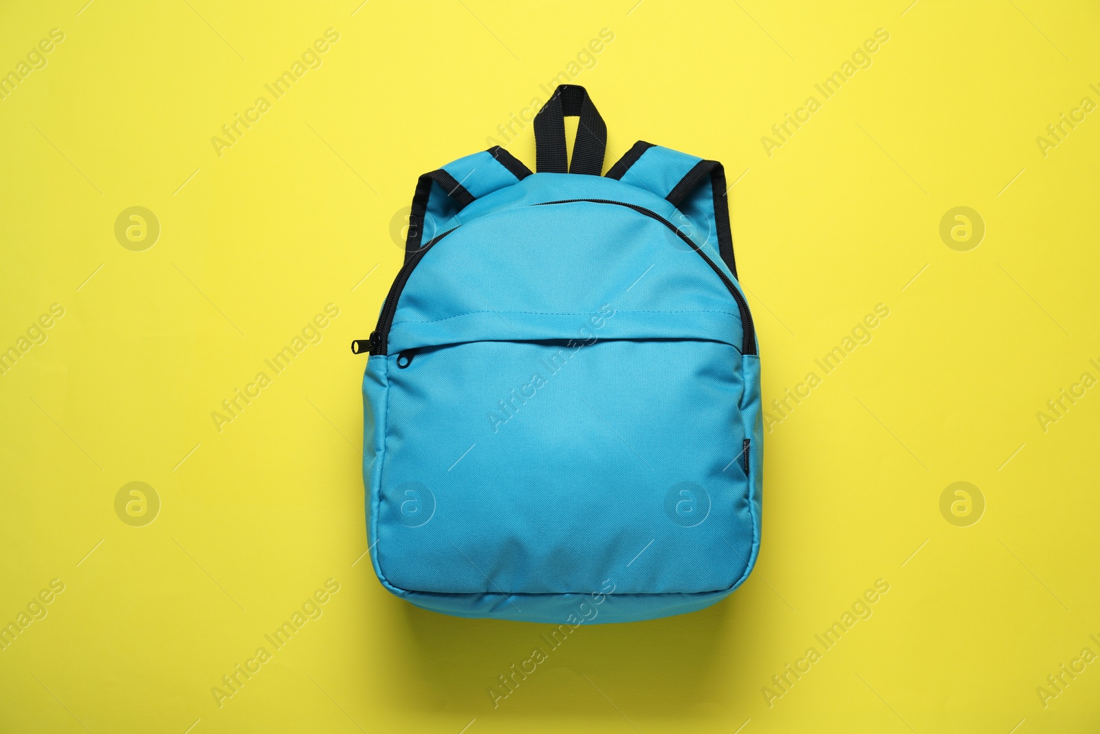 Photo of Stylish light blue backpack on yellow background, top view