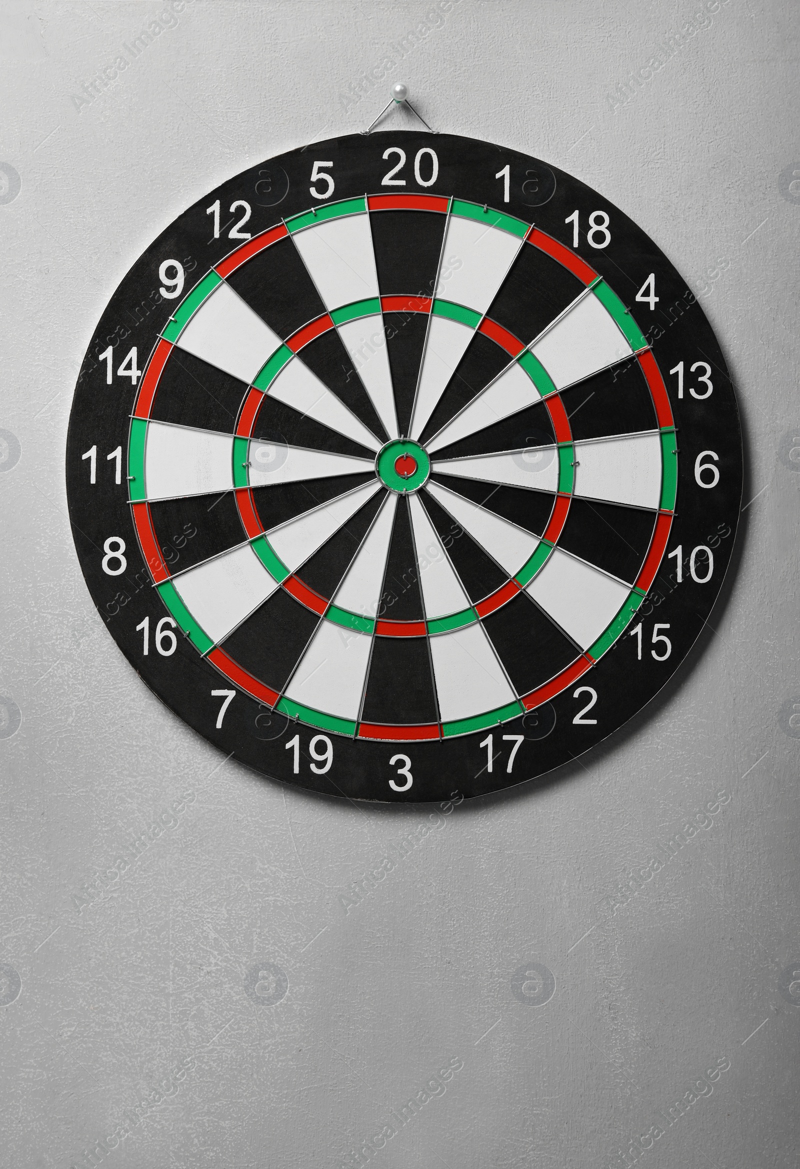 Photo of Dart board hanging on grey concrete wall