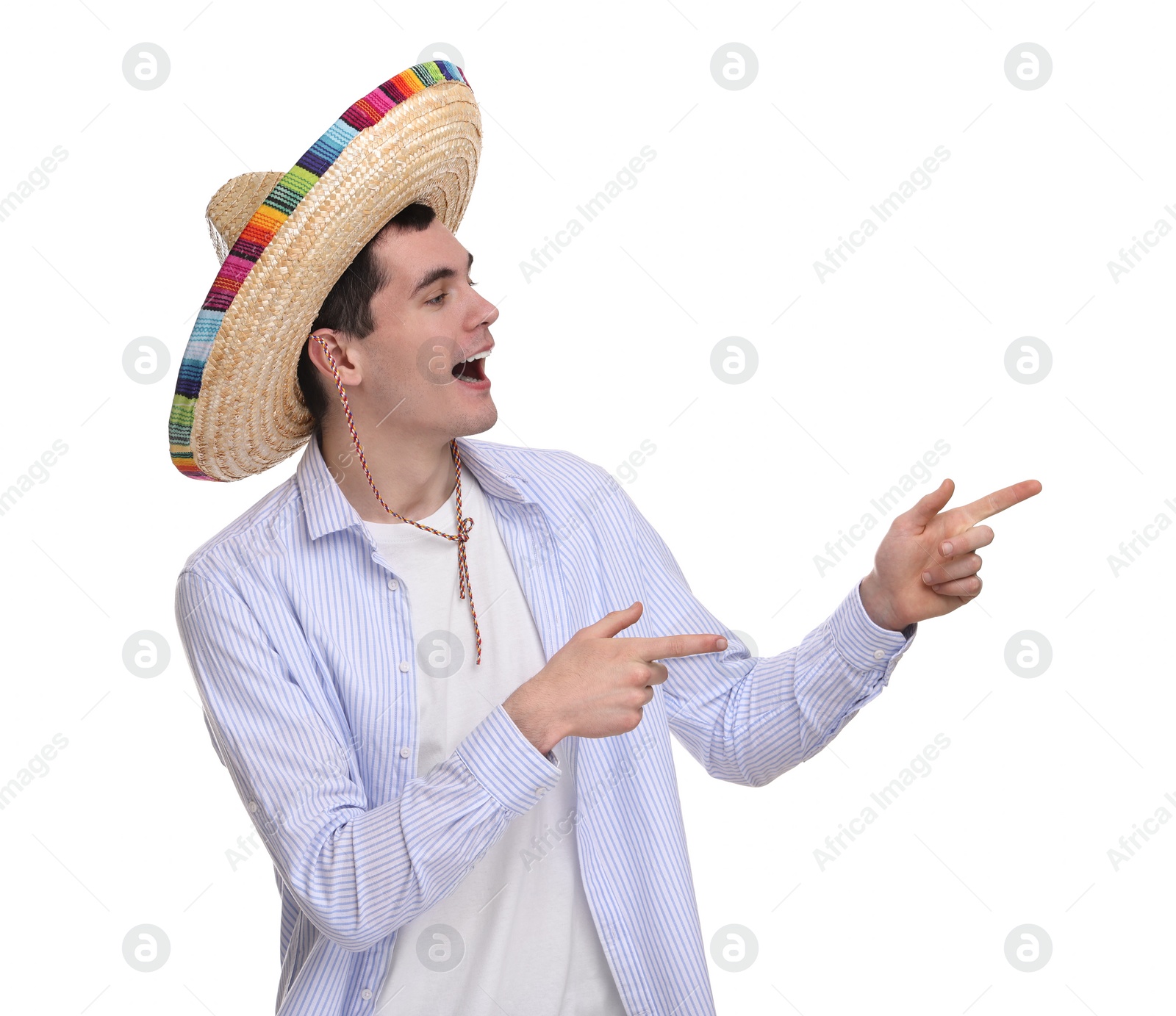 Photo of Young man in Mexican sombrero hat pointing at something on white background