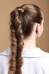 Woman with braided hair on brown background, back view