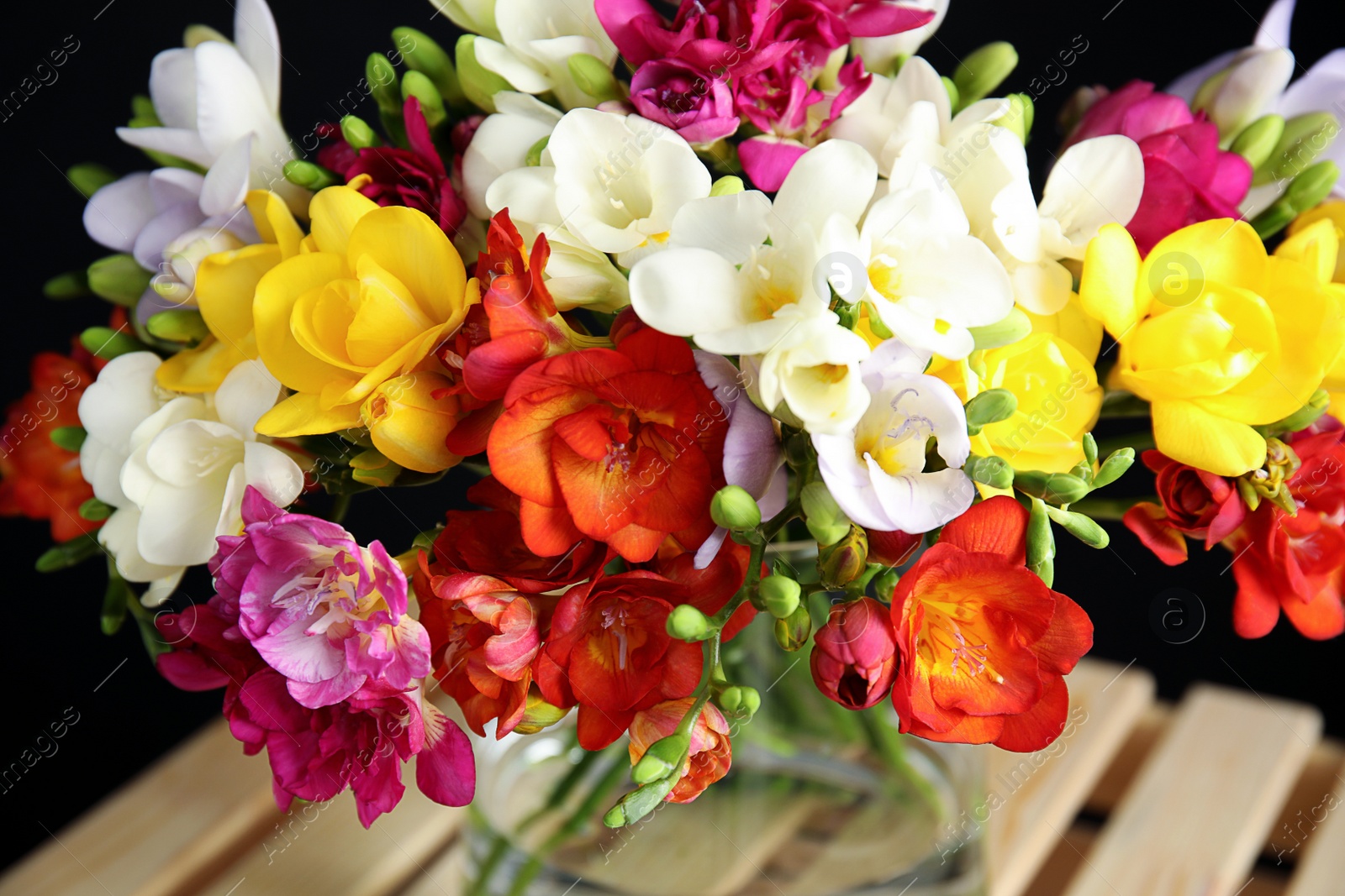 Photo of Bouquet of spring freesia flowers in vase on stand, closeup