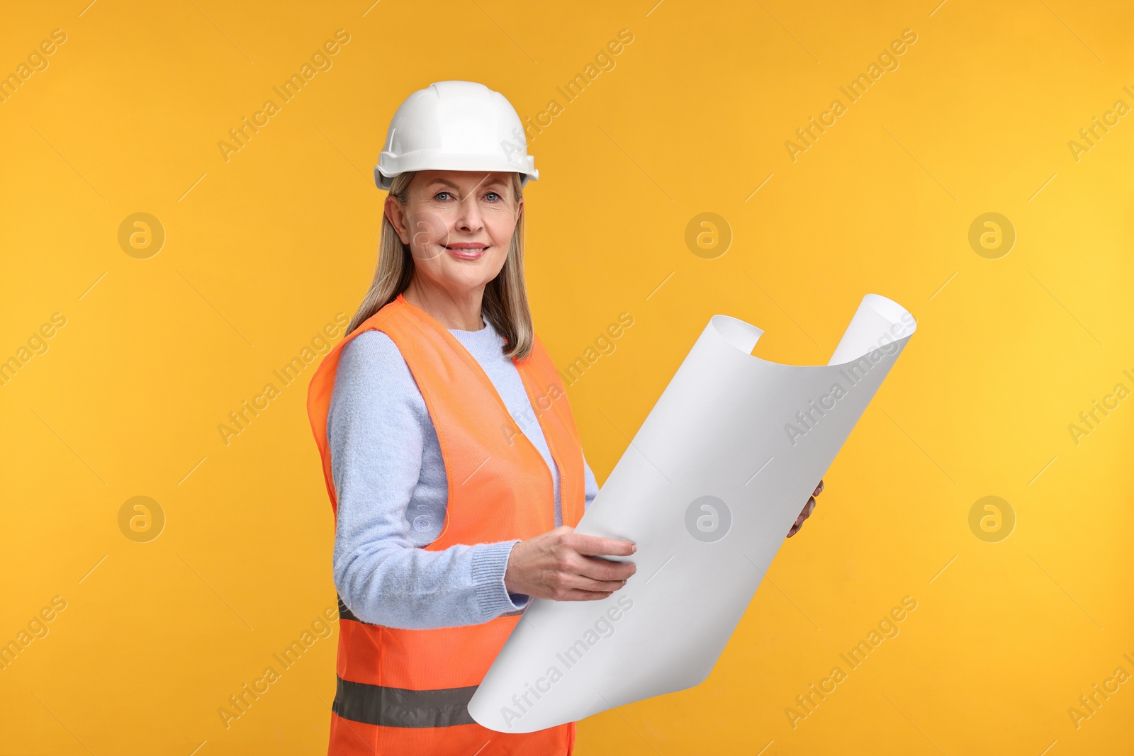 Photo of Architect in hard hat with draft on orange background