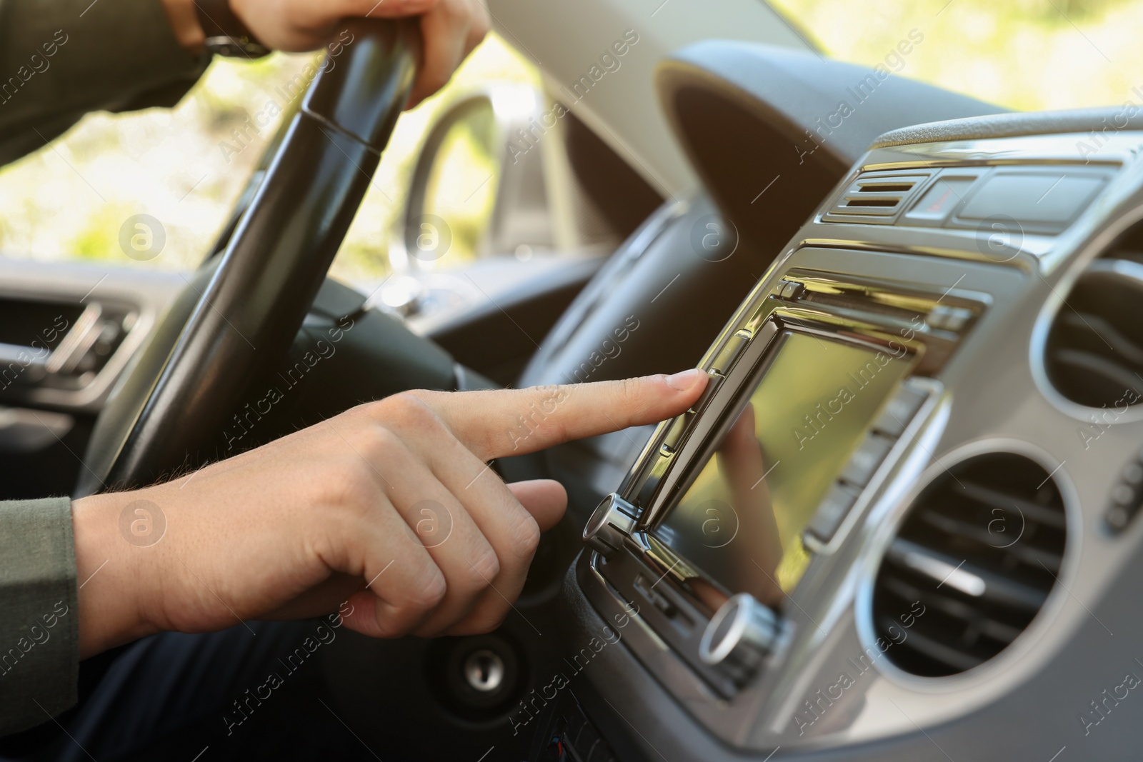 Photo of Choosing favorite radio. Man pressing button on vehicle audio in car, closeup