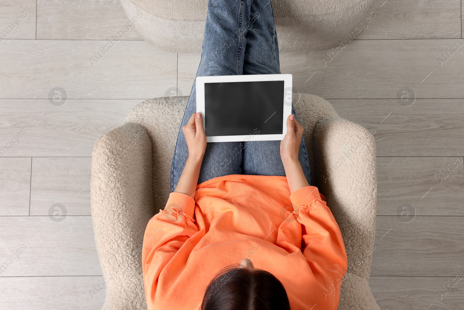 Photo of Woman working with tablet in armchair, top view