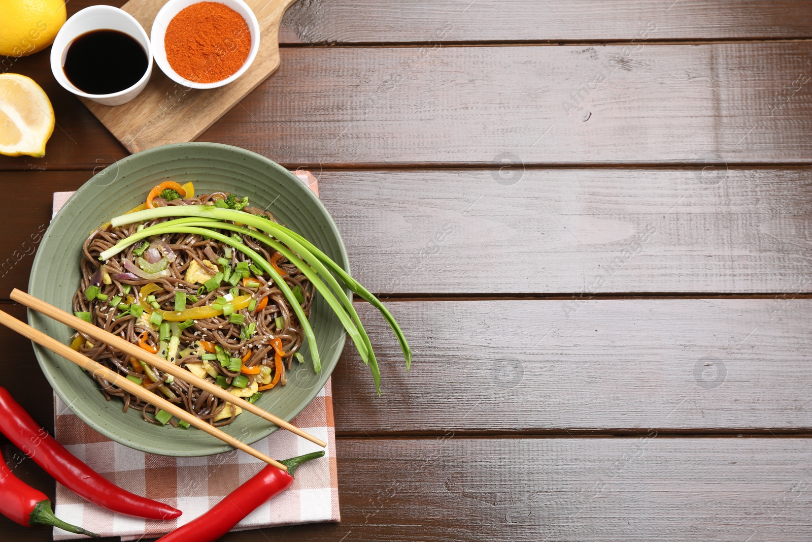 Photo of Stir-fry. Delicious cooked noodles with chicken and vegetables in bowl on wooden table, flat lay. Space for text