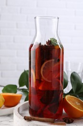 Photo of Delicious punch drink in bottle, spices and citrus fruits on white table