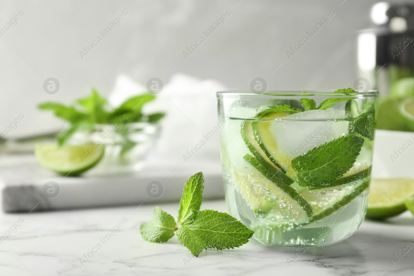 Photo of Refreshing beverage with mint and lime in glass on table