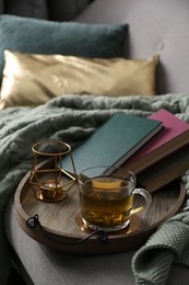 Photo of Stylish tray with different interior elements and tea on sofa