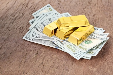 Photo of Shiny gold bars and dollar bills on table