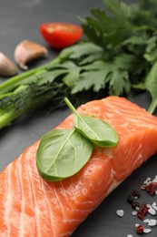 Photo of Fresh salmon and ingredients for marinade on black table, closeup