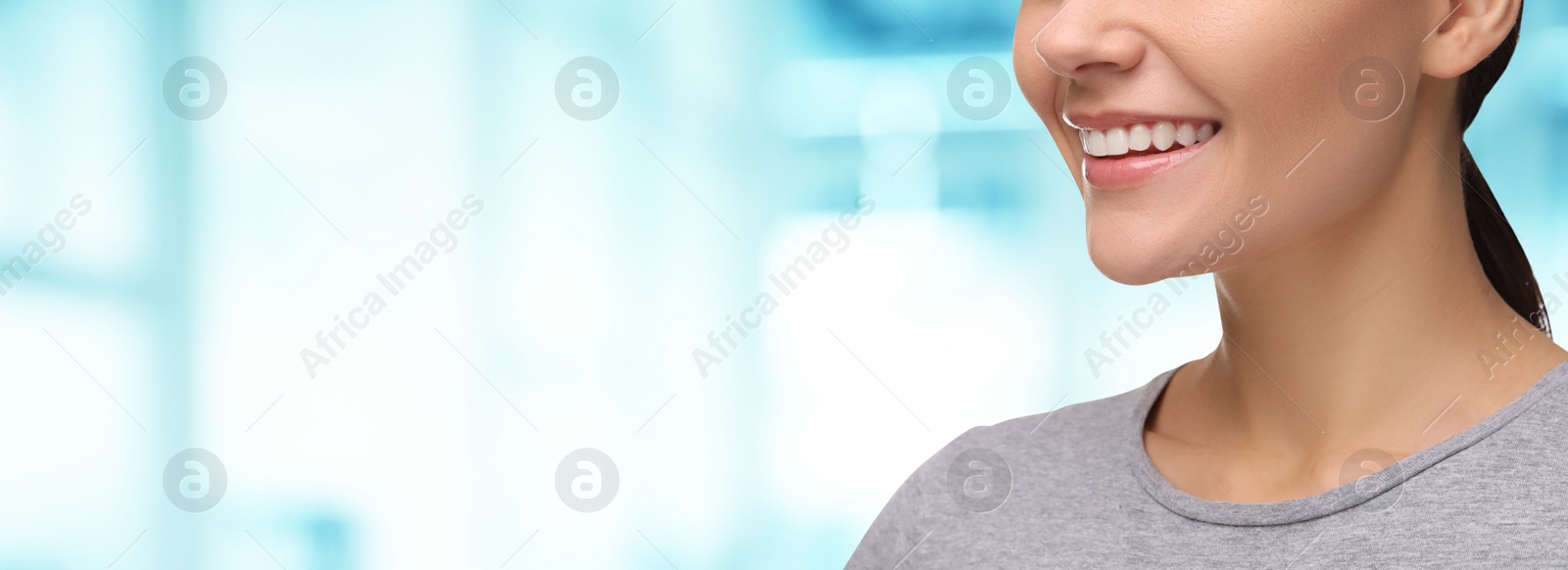 Image of Woman with clean teeth smiling on blurred background, closeup. Banner design with space for text