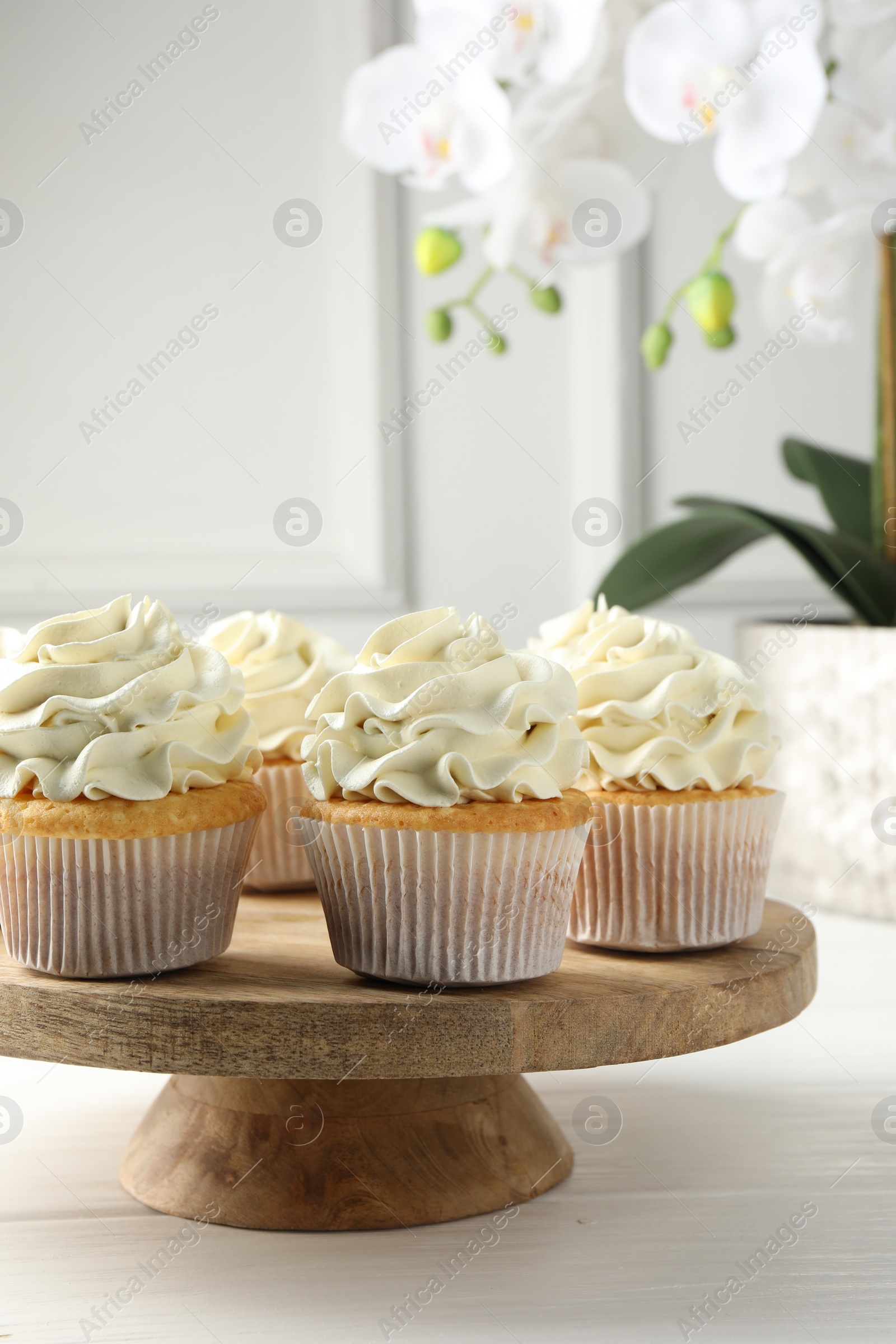 Photo of Tasty vanilla cupcakes with cream on white wooden table