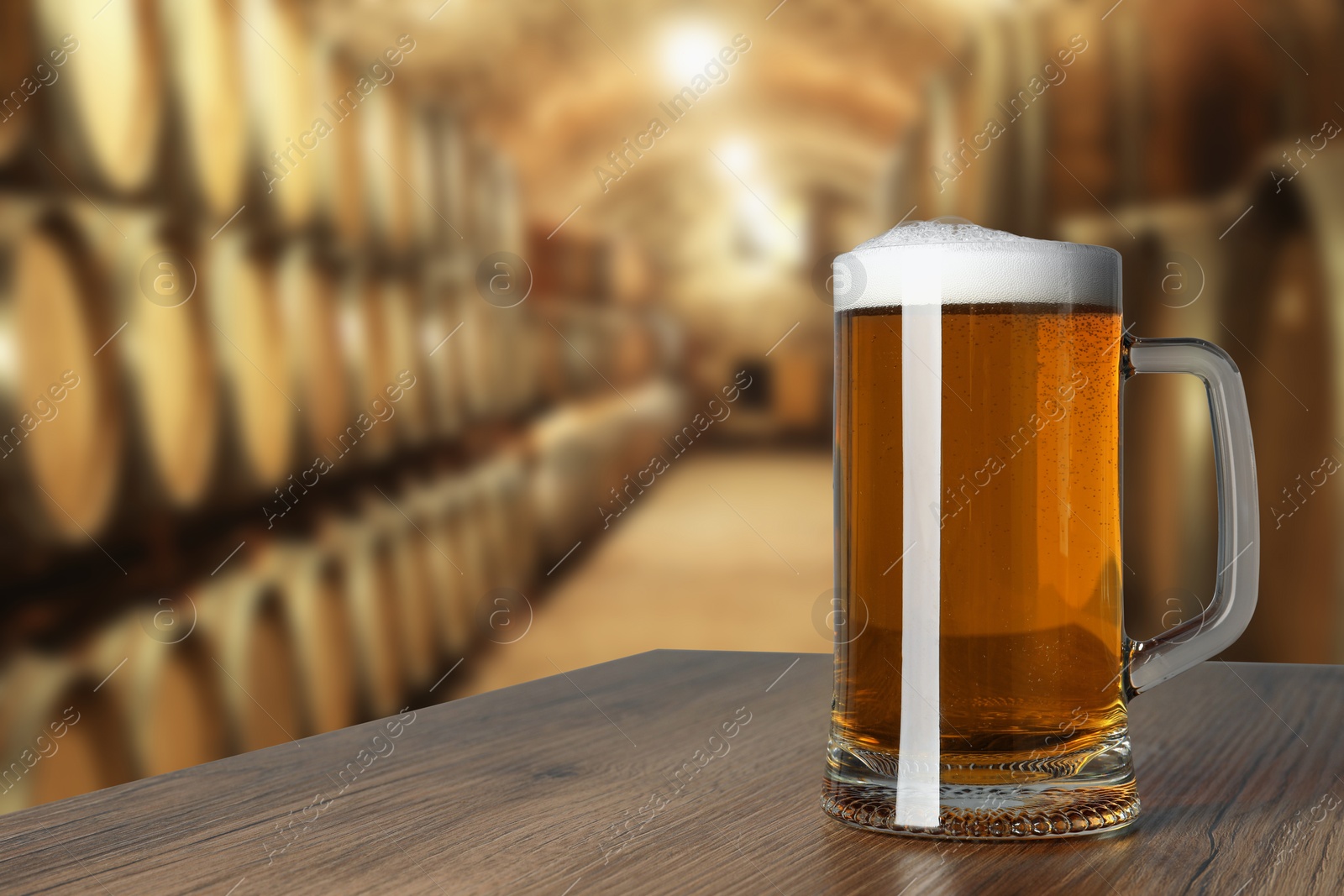 Image of Mug with fresh beer on wooden table in cellar, space for text