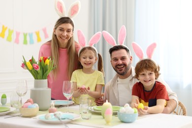 Photo of Easter celebration. Portrait of happy family with bunny ears at served table in room