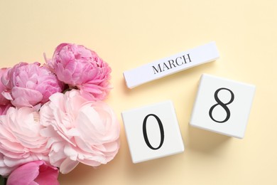 International Women's day - 8th of March. Wooden block calendar and beautiful flowers on beige background, flat lay