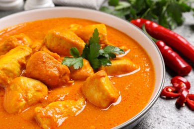 Photo of Bowl of delicious chicken curry on grey table, closeup