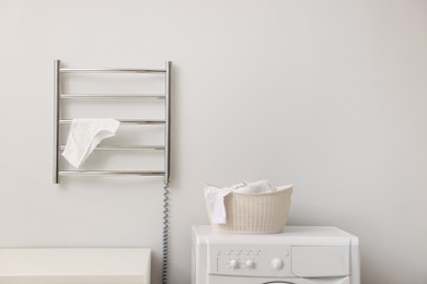 Photo of Heated towel rail with underwear on white wall in bathroom, space for text