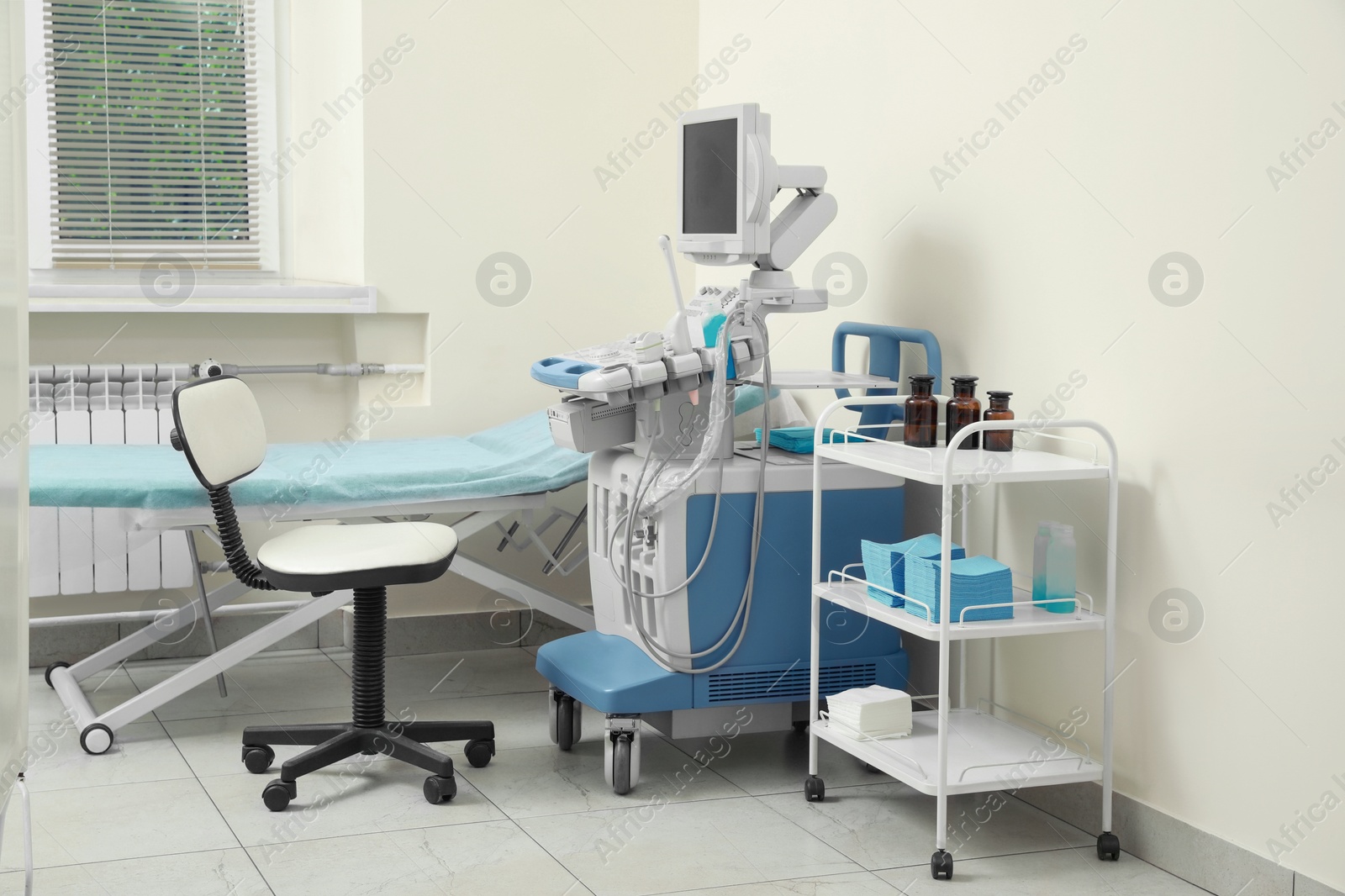 Photo of Ultrasound machine, chair, medical trolley and examination table in hospital